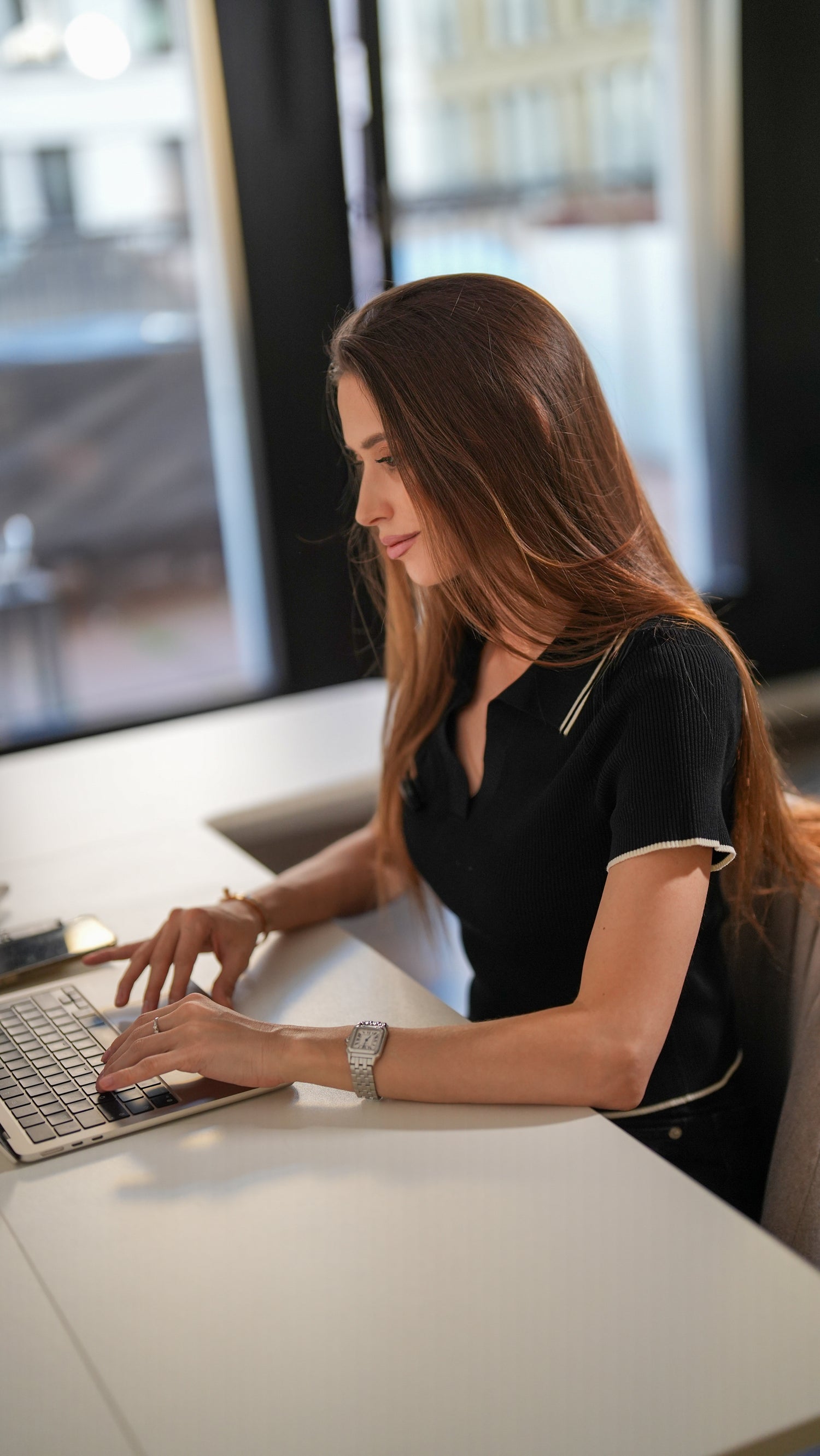 A young lady using a laptop at Maidesite Canvas desk near the window